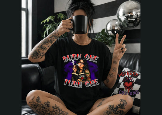 Person wearing a black t-shirt with graphic design, holding a mug and making a peace sign.
