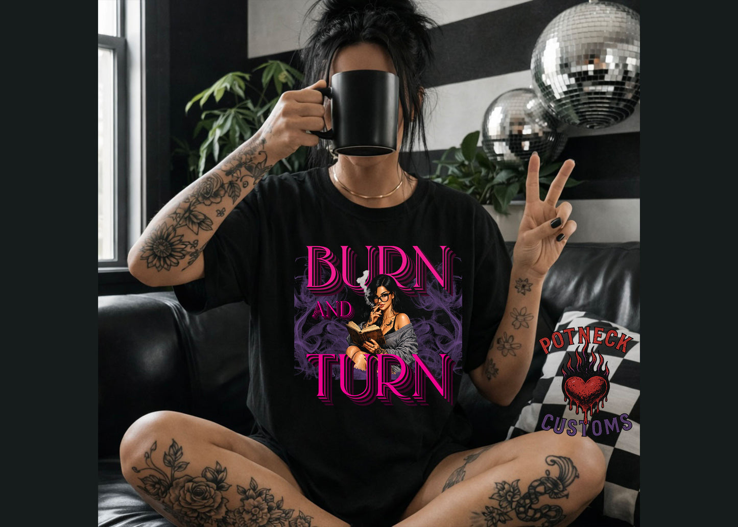 Person wearing a black t-shirt with 'Burn and Turn' design, holding a mug in a room with disco balls and plants.